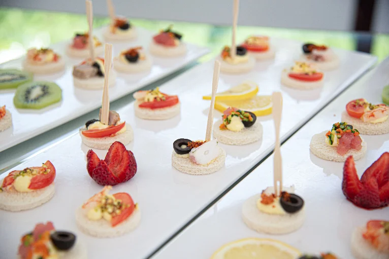 Feine Canapés mit Tomate, Olive und Erdbeeren auf weißen Platten