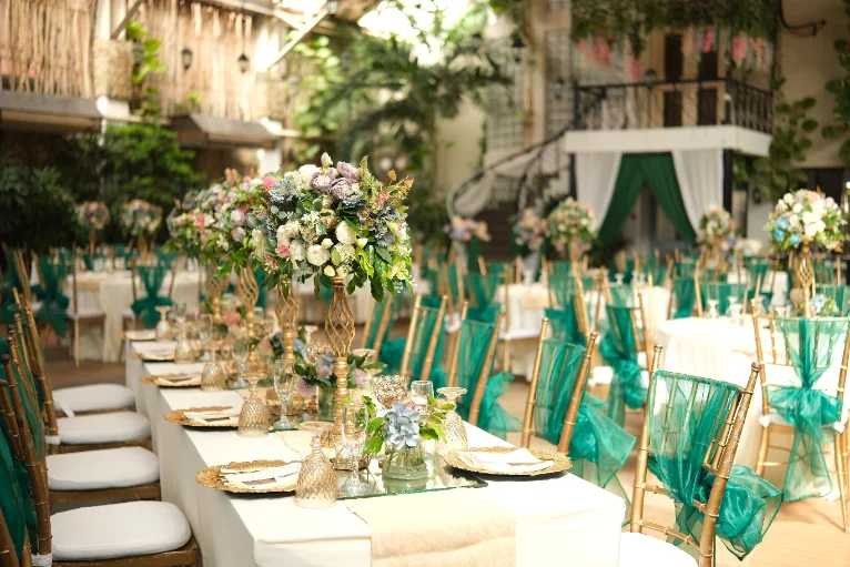 Festlich geschmückte Hochzeitstafel mit Blumengestecken und goldenen Stühlen